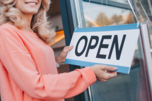 Ultimate Guide To Hiring A Small Business Lawyer - woman holding open sign store