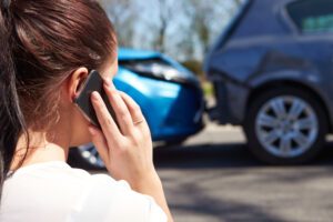 A woman on the phone after a car accident, asking if she can claim a car accident without a police report.