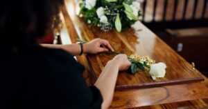A woman placing a flower on a coffin. Five things to do after a wrongful death in Virginia.