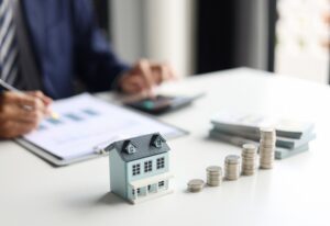 A model house next to a stack of coins. Does renters insurance cover personal injury?