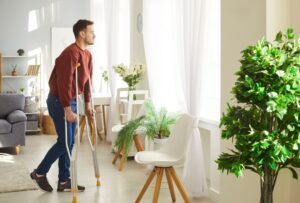 An injured man on crutches, wondering, “How are personal injury settlements paid out?”
